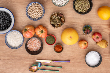 Top view image of grapefruit and rounded tomatoes in bowls with sea and Himalayan salt, chickpeas and rice, dill and paprika, apples and persimmons