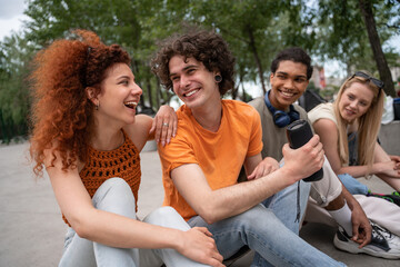 happy young man holding portable music speaker near interracial friends.