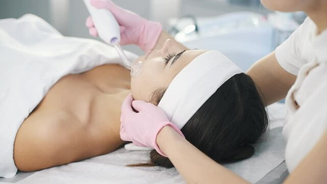 Close up view of woman that lying down in spa salon and have face cleaning procedure by using special modern device