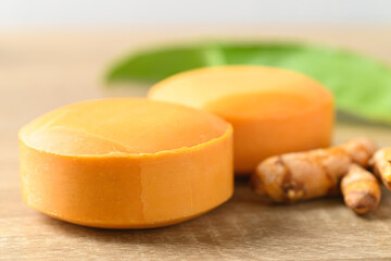 Turmeric soap and fresh turmeric root on wooden table, herbal organic soap for skin care