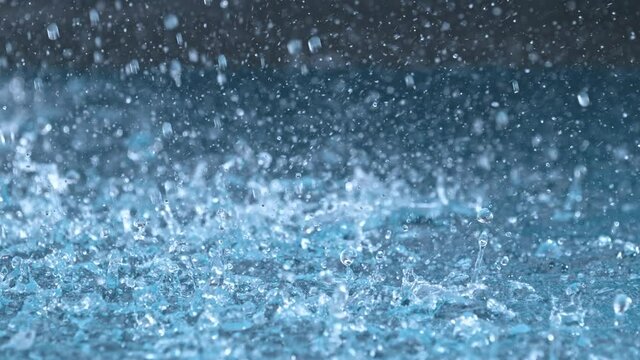 Super Slow Motion Shot of Droplets Raining on Blue Water Surface at 1000 fps.