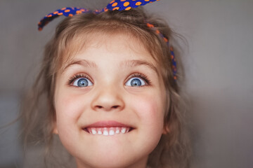 portrait of girl with blue eyes and cheerful funny emotion close-up, selective focus on eyes