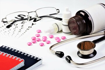 Medical concept. A background of medications, a stethoscope, glasses with diopters and an ophthalmological vision test.