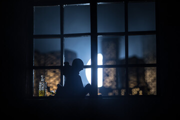 Fototapeta premium A realistic dollhouse living room with furniture and window at night. Romantic couple sitting on window. Artwork table decoration with handmade realistic dollhouse. Selective focus.