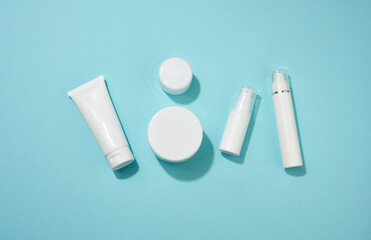 jar, bottle and empty white plastic tubes for cosmetics on a blue background. Packaging for cream, gel, serum, advertising and product promotion, mock up