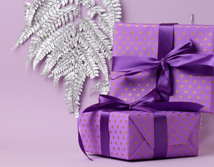 boxes packed in festive purple paper and tied with silk ribbon on a purple background, gift, surprise