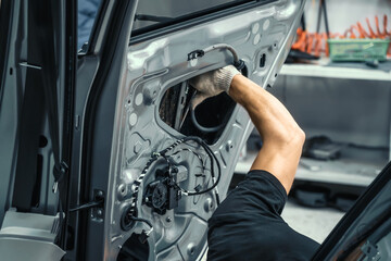 Auto service worker disassembles car door for repair, restoration, tuning car sound or installing...