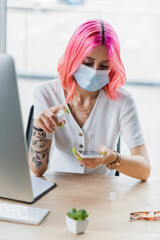 young businesswoman in medical mask spraying sanitizer on smartphone in office.
