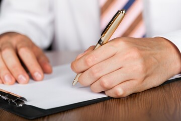 Closeup of a Businessman Writing on Clipboard