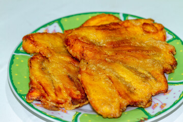 Fried bananas are served on a small plate, usually consumed with tea or coffee, oily and high in calories
