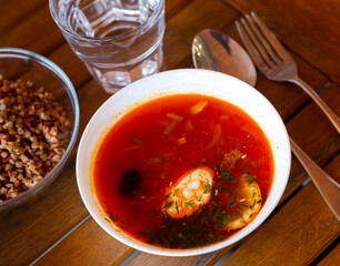 Traditional solyanka on broth with assorted meat served with sour cream