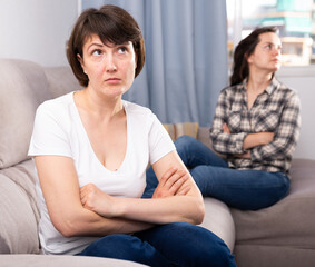 Portrait of upset adult woman after conflict with young sister at home interior