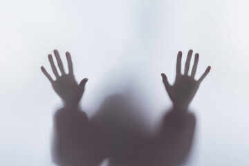 Blurry silhouette of person touching glass with hands