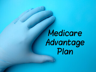 Hand wearing latex glove with text Medicare Advantage Plan on blue background.