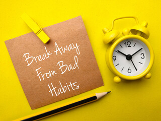 Pencil,clock and brown card with text Break away from bad habits on yellow background.