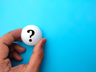 Fototapeta na wymiar Hand holding pingpong ball with question symbol on a blue background.