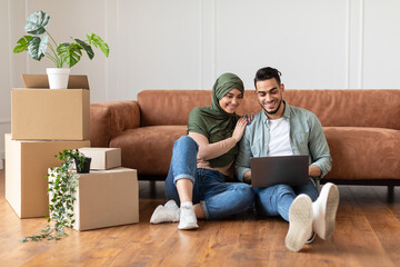 Happy muslim man and woman using laptop after relocation