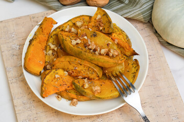 Plate of baked pumpkin sprinkled herbs and walnuts. 