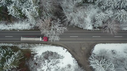 Winter trip  driving truck and cars driving at a straight road in a snowy landscape, filmed straight from above in 4K
