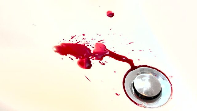 Blood dripping and flowing into sink. Fresh red blood splat on white porcelain with specks from the impact. Blood draining from white bathroom basin.
