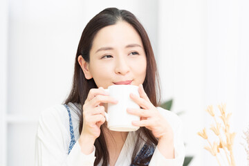 リビングでコーヒーを飲みながら考え事をする主婦