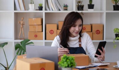 Obraz na płótnie Canvas Shipping shopping online ,young start up small business owner writing address on cardboard box at workplace.small business entrepreneur SME or freelance asian woman working with box at home