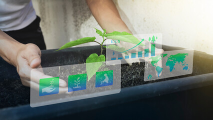 Hands are planting seedlings and icons are displayed on the screen. green energy and technology...