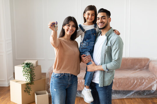 Happy family of three people showing keys of their apartment