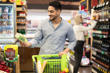 Arabic Male Doing Grocery Shopping Choosing Vegetables In Modern Supermarket