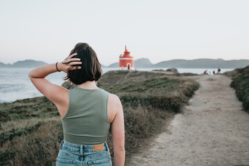 Back image of a young backpack traveler hiker during an stunning sunset coastline scenario, hipster...