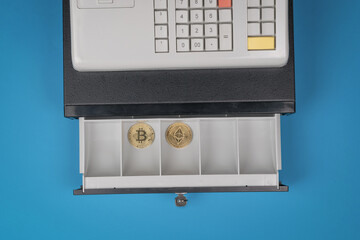 Two digital coins in an open cash register on a blue background. The concept of replacing money...