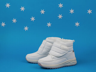 Stylish women's white sneakers on a blue background with snowflakes.