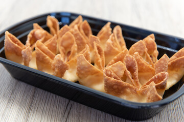 Fried wontons all symmetrically folded and arranged on a plate as a chinese food appetizer.