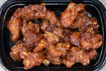 Overhead view of bowl of crispy breaded orange chicken smothered in a spicy sauce for great Chinese fast frood.