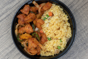 Overhead view of tradiional Chinese fast food meal with fried rice and seasoned chicken in a perfect size bowl.