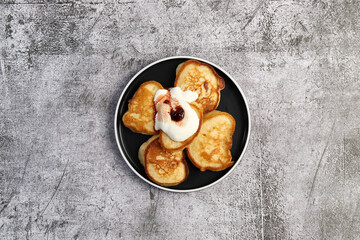 Fluffy buttermilk pancakes with berry jam on a round plate on a dark gray background. Top view, flat lay