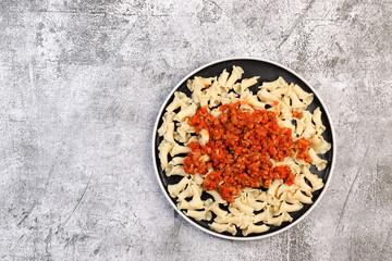 Traditional pasta bolognese on a round plate on a dark grey background. Top view, flat lay