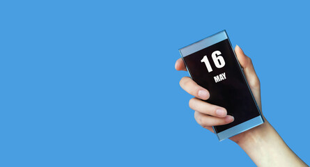 may 16. 16th day of the month, calendar date.Woman's hand holds mobile phone with blank screen on blue isolated background.Spring month, day of the year concept