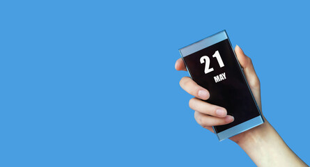 may 21. 21th day of the month, calendar date.Woman's hand holds mobile phone with blank screen on blue isolated background.Spring month, day of the year concept