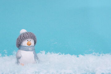 Toy penguin on the snow and blue background. The minimalistic style of the New Year's card.