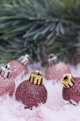 Christmas balls on snow and pink background. The minimalistic style of the New Year's card.