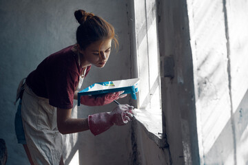 woman painter paints window with brush renovation interior decoration