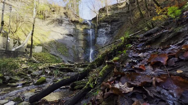 Super wide shot of the "Zillhauser" Waterfall near Albstadt, Germany. Trees and leaves in the foreground. Camera very low to the ground.