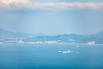 Cargo Container Ship on the sea near the coast and mountains