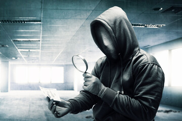 Criminal man in a hidden mask using magnifying glass while holding the money while robbery