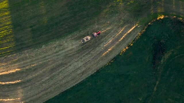 Top-Down Aerial Of Tractor Pulling Baling Machine In Late Afternoon Light In Rural Pennsylvania, U.S.A.