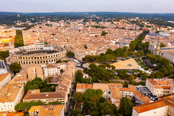Fototapeta premium Panoramic aerial view of ancient French city of Nimes overlooking brownish tiled roofs of residential buildings in historic district and antique Arena