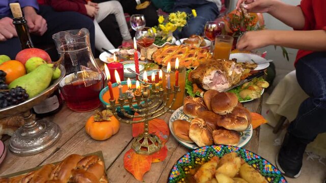 Hanukkah - Jewish Festival of Lights. Menorah candles. Festive Hanukkah dinner at home with family. Traditional kosher food and drink on the table - sufganiyot, latkes, cottage cheese and cheese meals