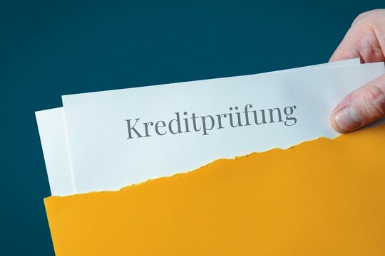 Kreditpr&uuml;fung (Bonit&auml;t). Brief-Umschlag (gelb) &ouml;ffnen. Hand zieht Dokument heraus