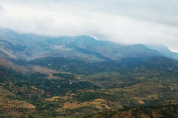 Moroccan landscape with foggy mountains and fields.